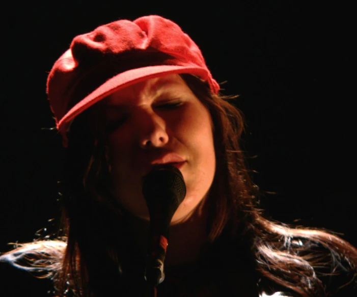 a woman in a red hat is singing into a microphone