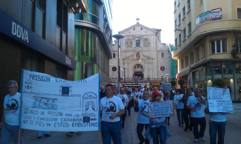 several protestors walking down a city street holding up placares