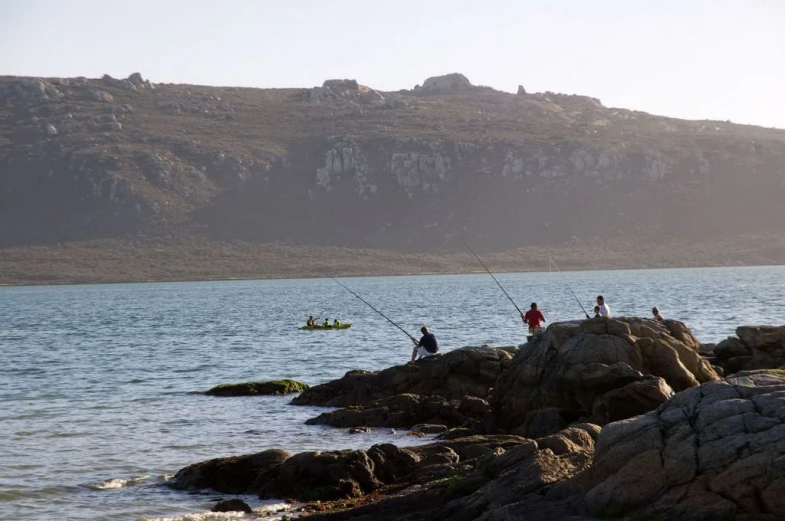 people fishing off the shore next to a large body of water