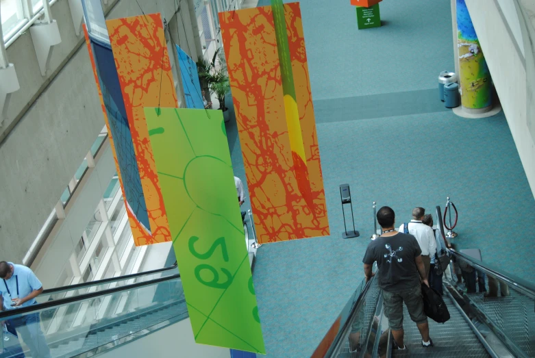 an escalator with paintings on the walls and people walking up one side