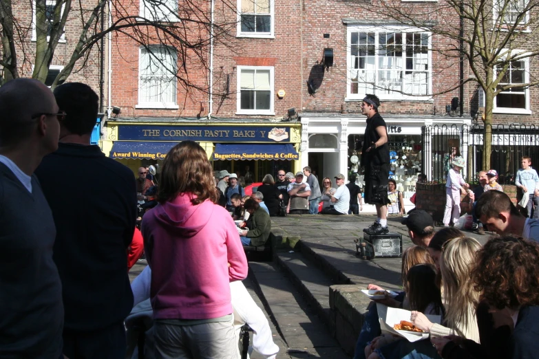 a crowd watches a performance in front of a store