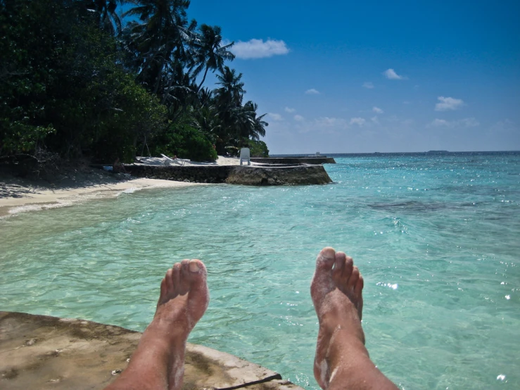 the view from a person's feet looking at an ocean and a small island