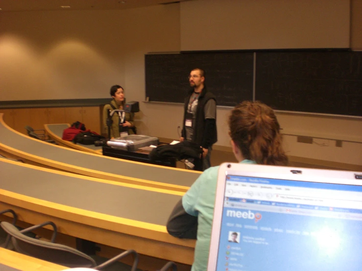 a group of people at the back of a lecture hall with their laptop computers