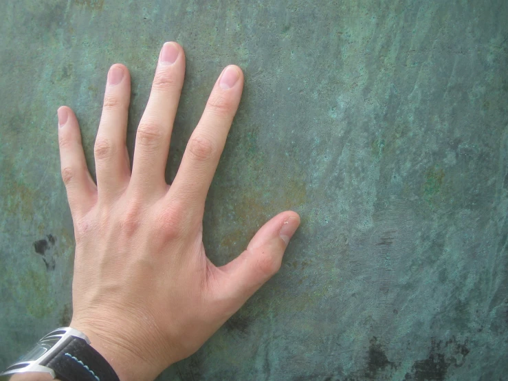 a hand laying on a wall next to the palm of a person