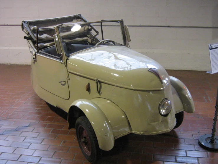 an old fashioned yellow car with a black roof