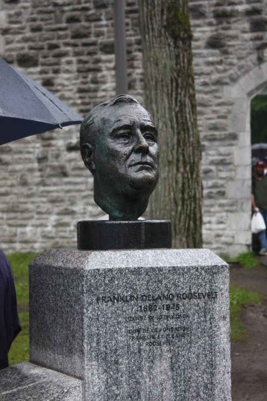 a person holds an umbrella over a bust of an old man