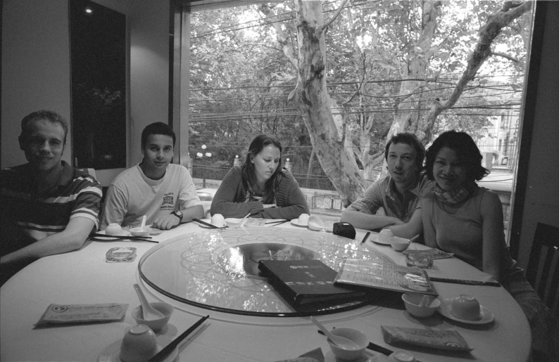 five people sit at a table looking through some papers