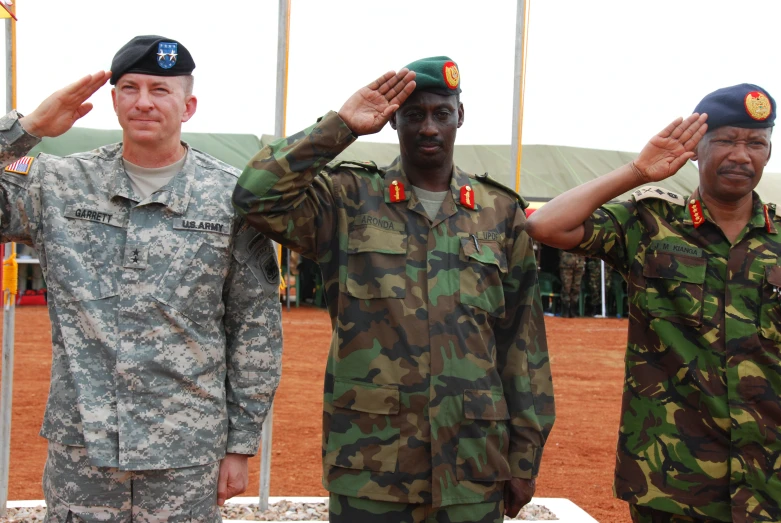 three men in military uniforms saluting each other