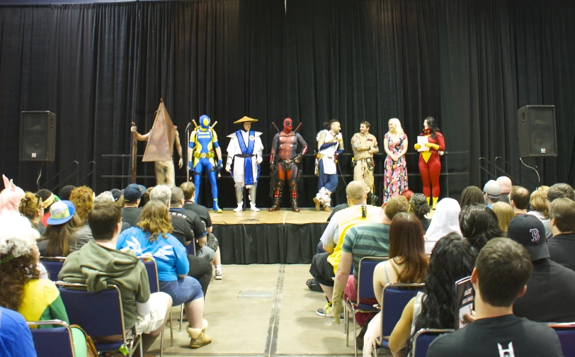 a group of people wearing costumes standing on a stage