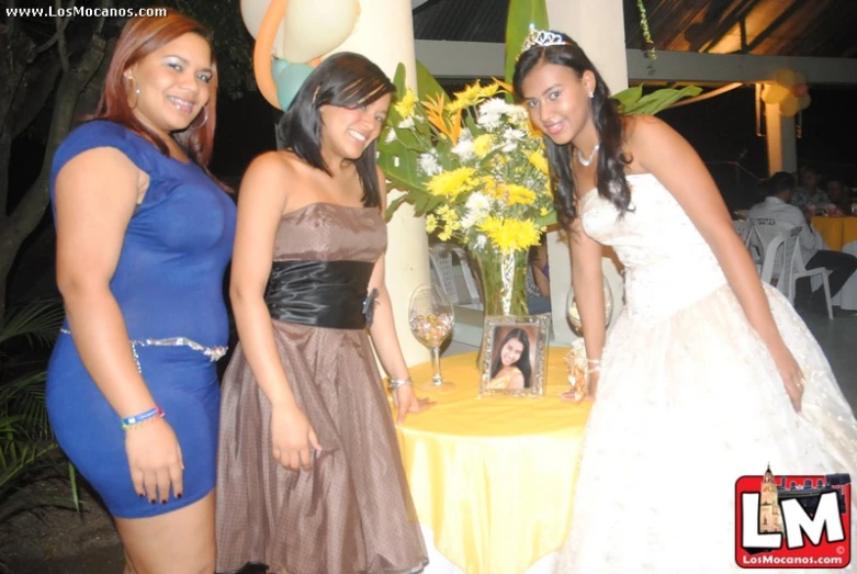 three beautiful ladies standing next to each other in dresses