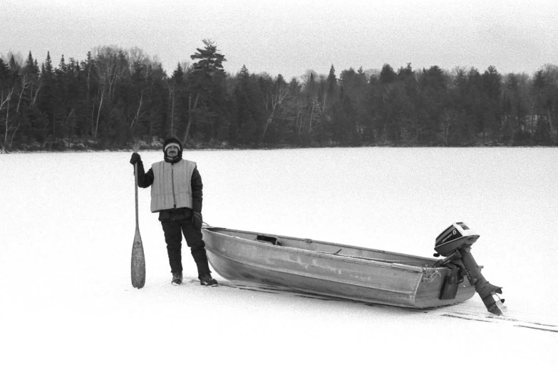 a person standing next to a boat in the snow