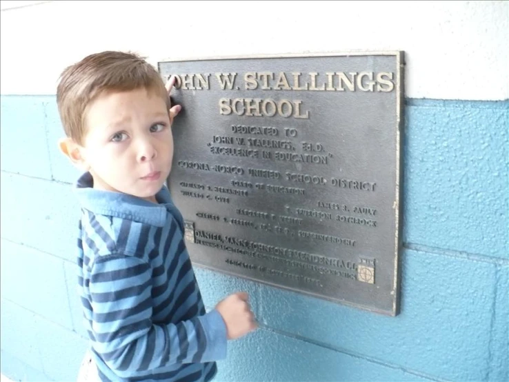 a  posing for a po next to a school sign