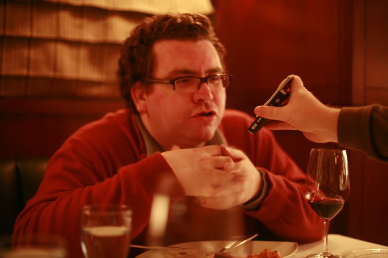 the man is eating at the table while being examined by someone else