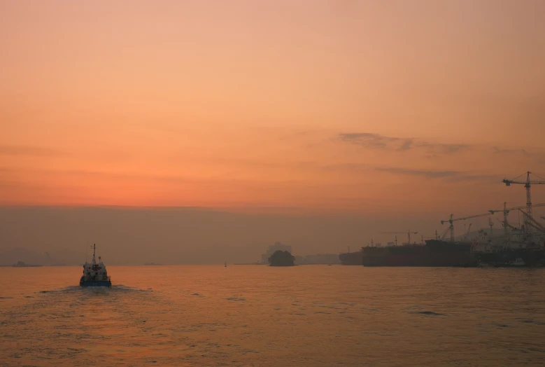 a ship sailing on the water with a sunset in the background