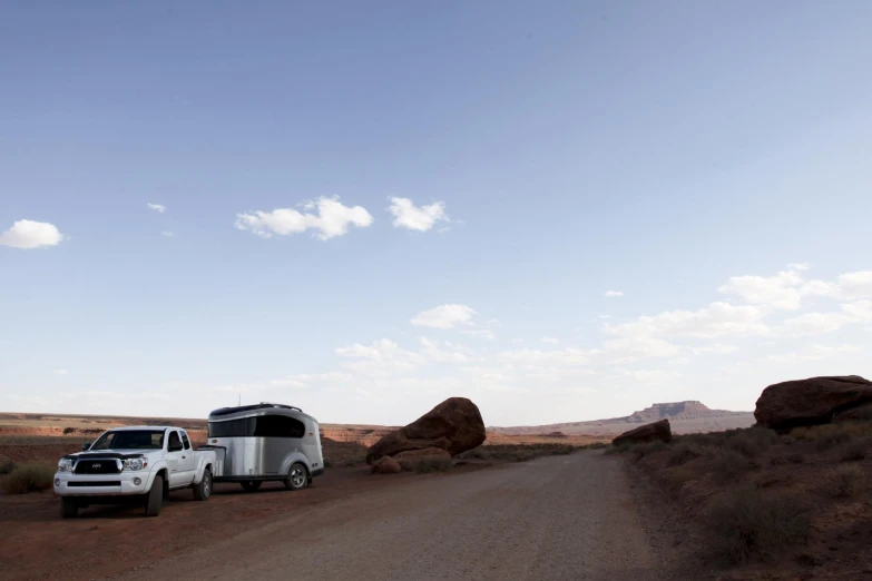 a truck towing a trailer and trailer parked in front of some rocks