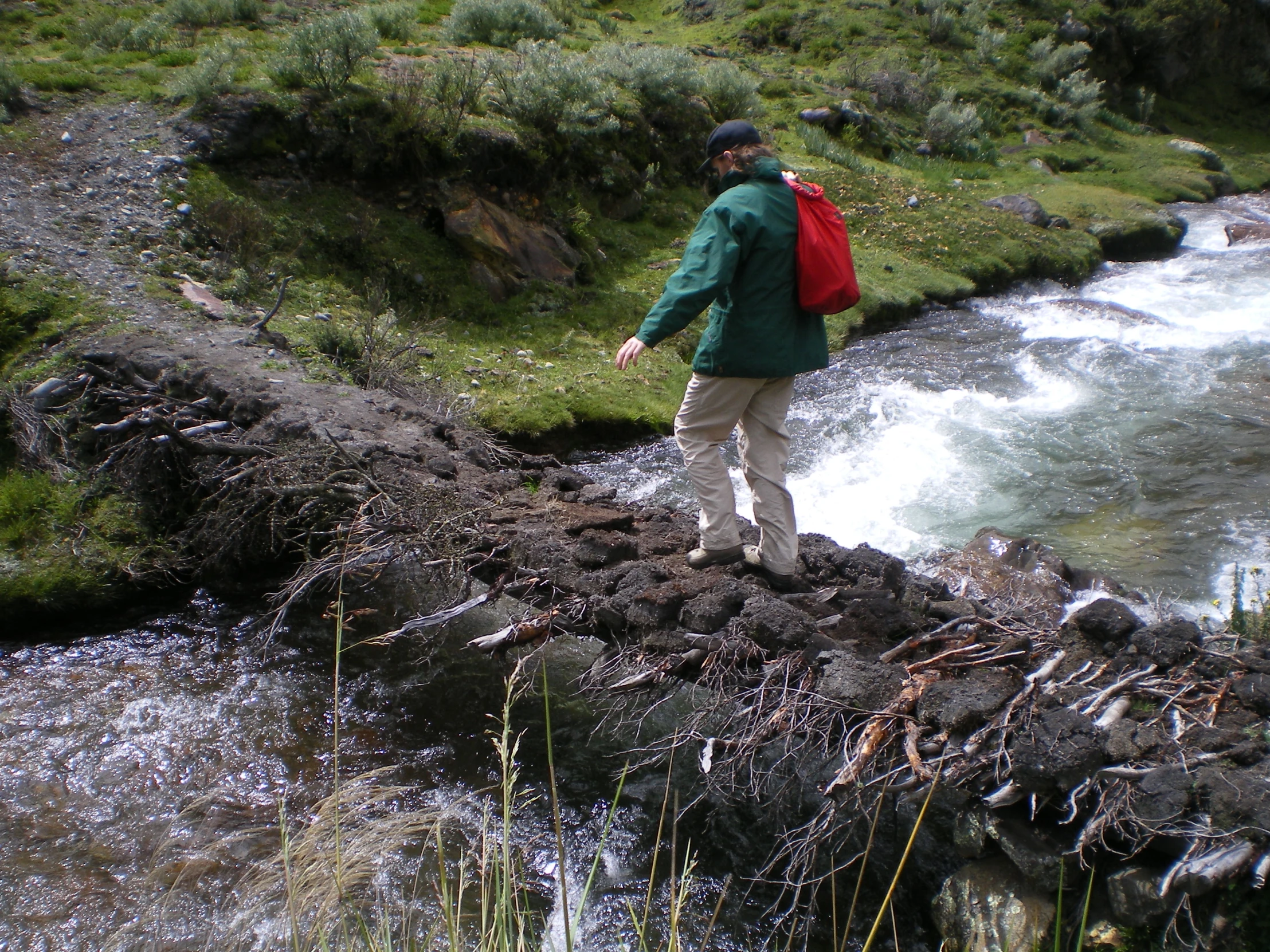 a man walking over a rock bridge in a river