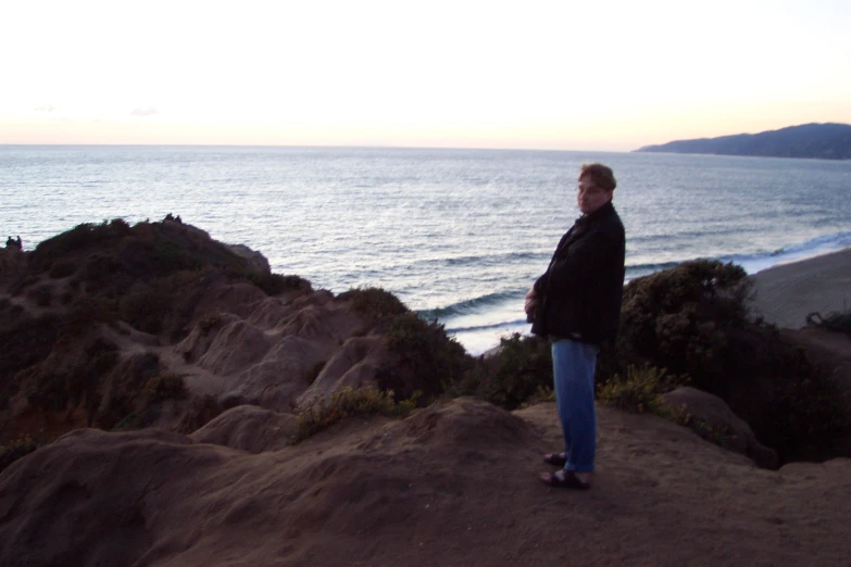 a woman standing on a cliff with water in the background