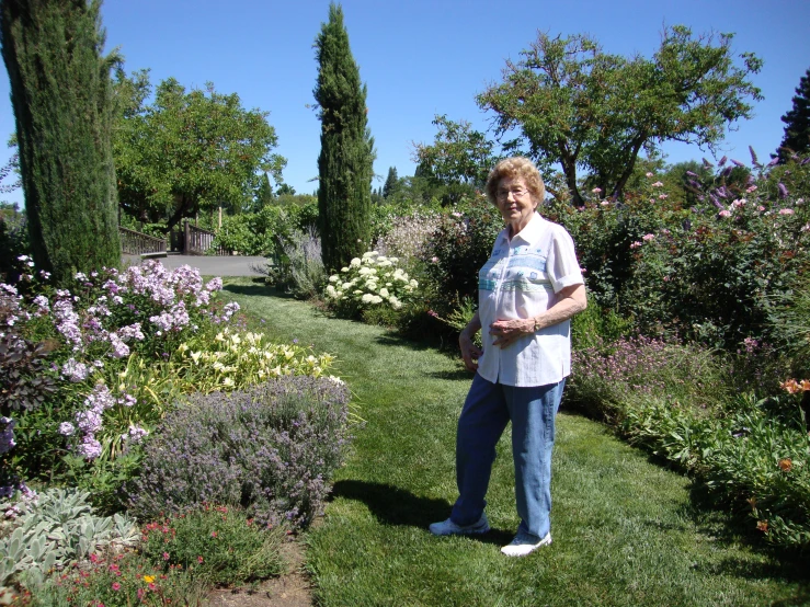 woman posing in a garden with flowers and trees