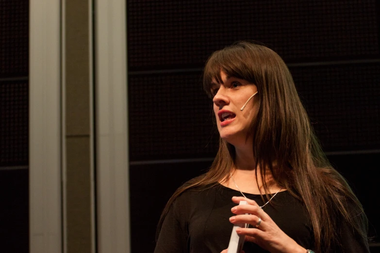 a woman is speaking at an event in a room