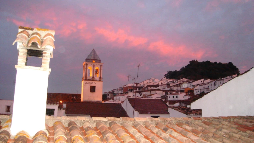 the rooftops of roofs and bell tower under a cloudy sky