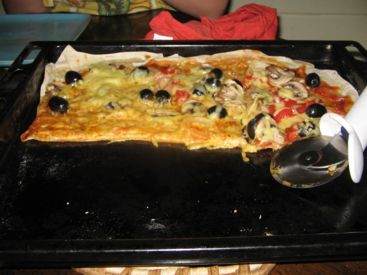 pizza on top of a pan with lots of olives