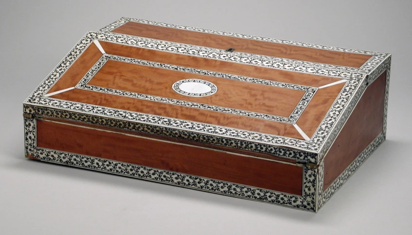 a small, handmade wooden jewelry box inlaid with elaborate carvings and mirrors