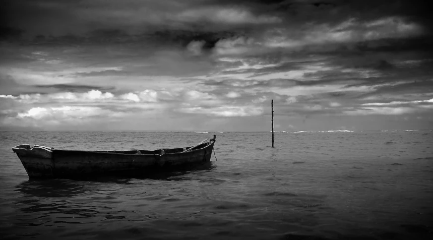 a small boat out in the ocean under a cloudy sky