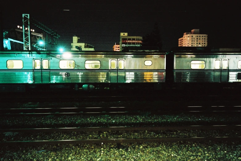 a train is sitting alone by some buildings at night