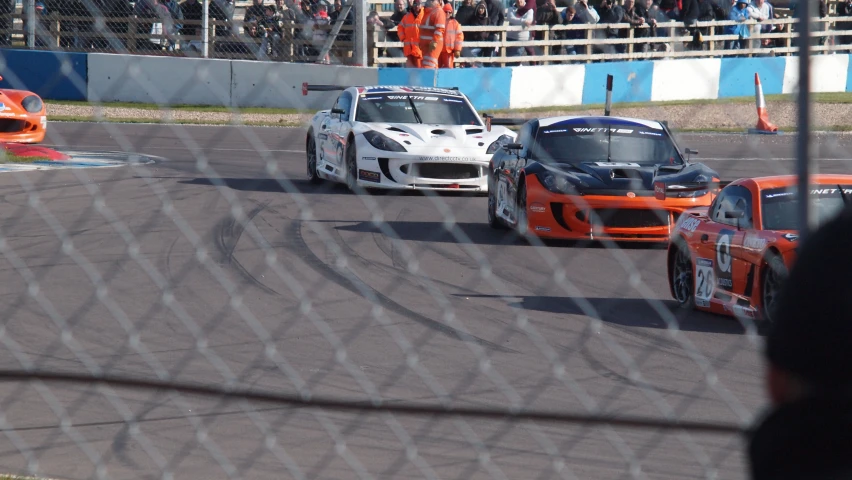 two racing cars driving around a track in front of an audience