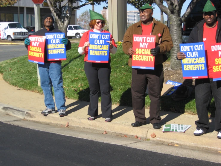 five people holding up signs on a street corner