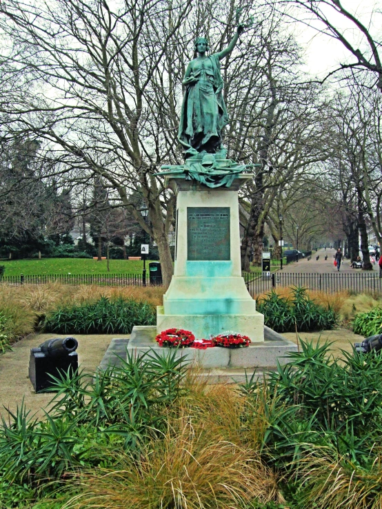 a statue in a park surrounded by bushes