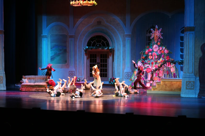 dancers performing on stage in front of lit christmas tree