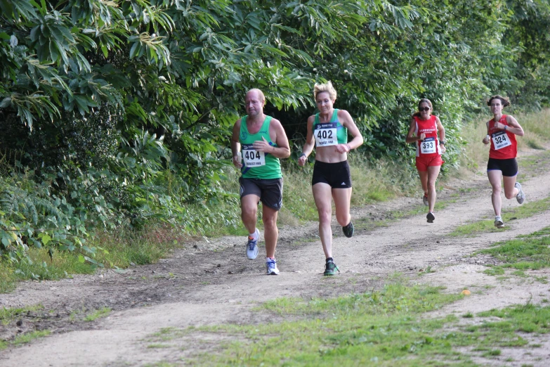 three young women running down a road next to a forest