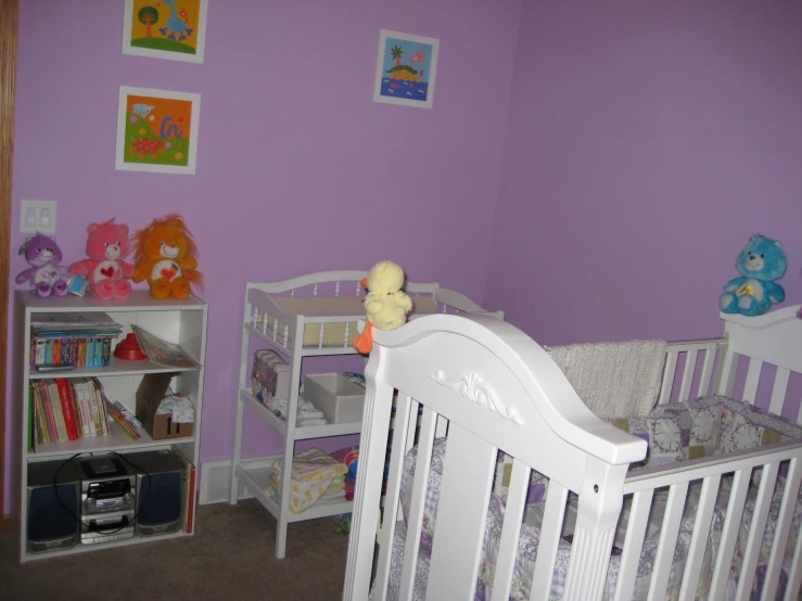 a bedroom with two white cribs and a purple wall