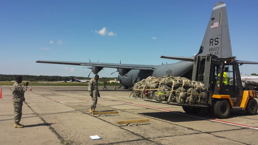 military personnel standing outside of jet with a loader