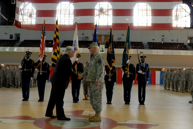 two military officials talking to one another in front of a group of men