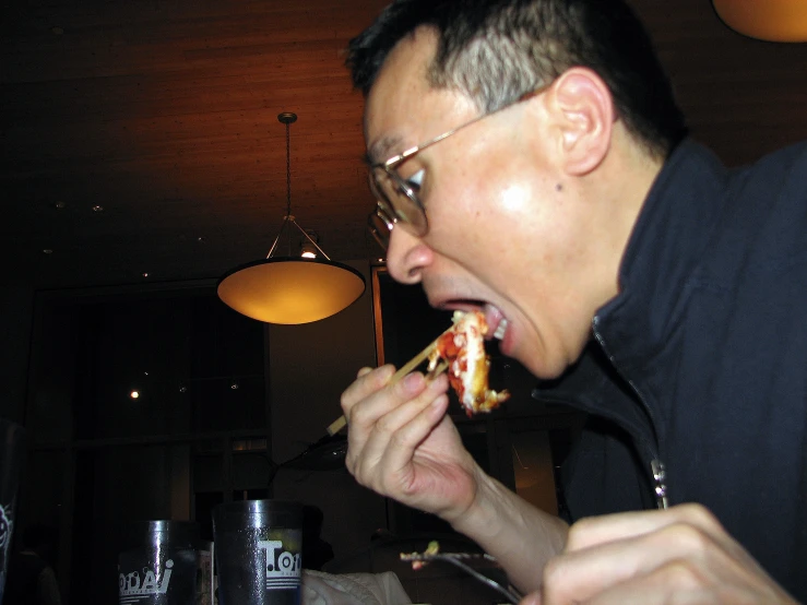 a man in glasses is eating food and sitting down