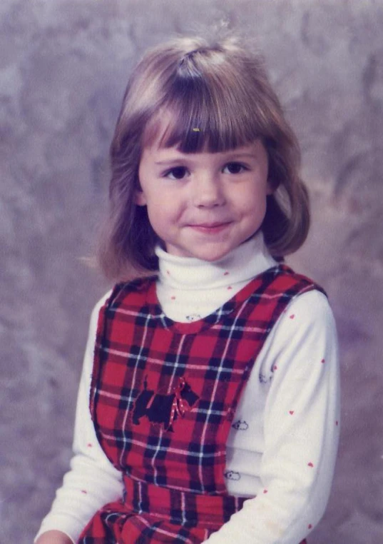a little girl in plaid is posing for a po