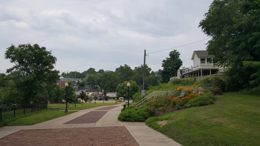 there is a paved path near flowers in the grass