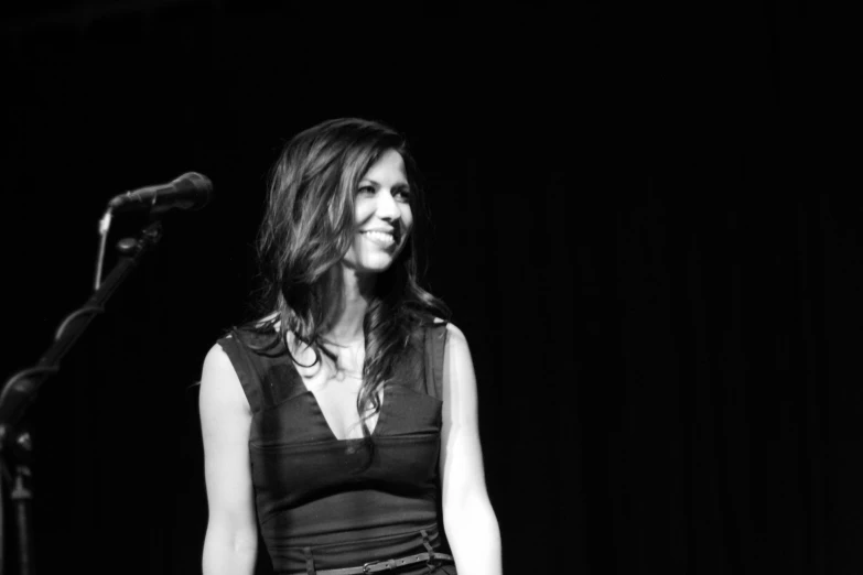 a woman is standing next to a microphone in the dark