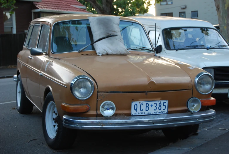 two small brown cars side by side and one cat sleeping