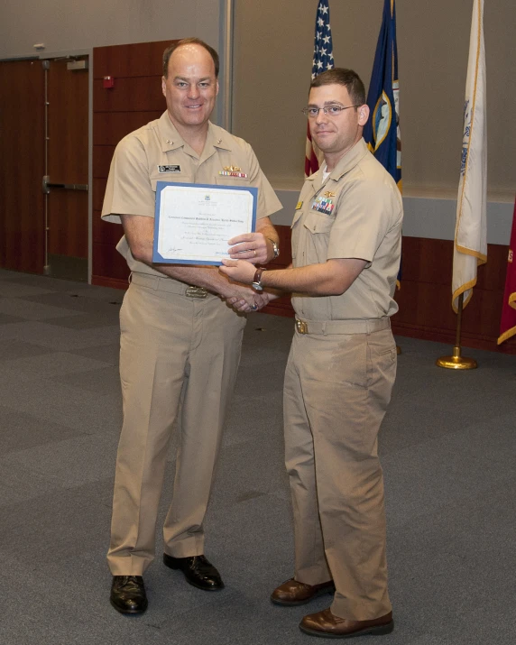 two people in uniform shaking hands with an award