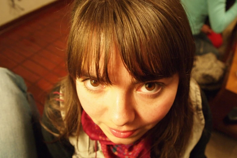 a woman with brown hair and bangs wearing a scarf