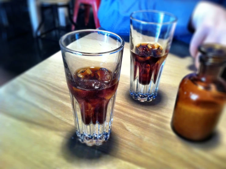 three glasses of beverage on top of a wooden table