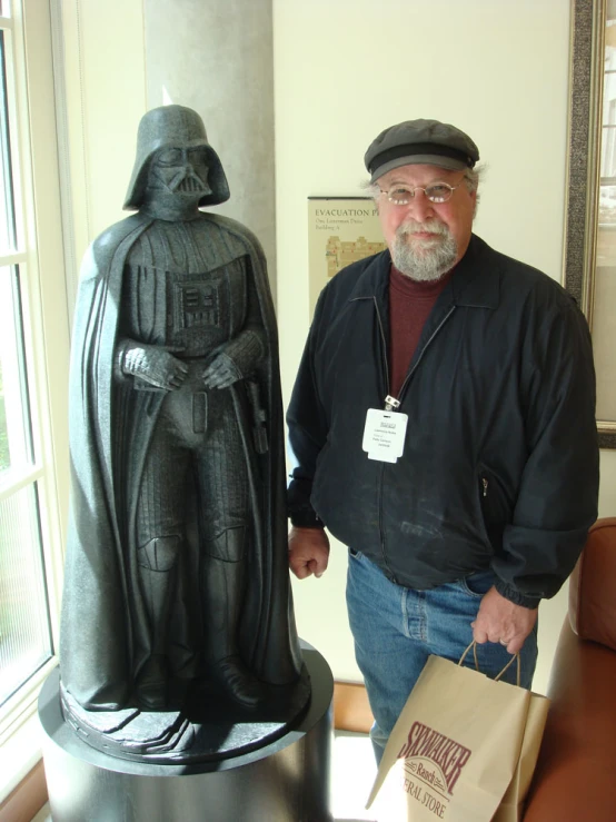 a man stands next to a statue with his hand on a paper bag