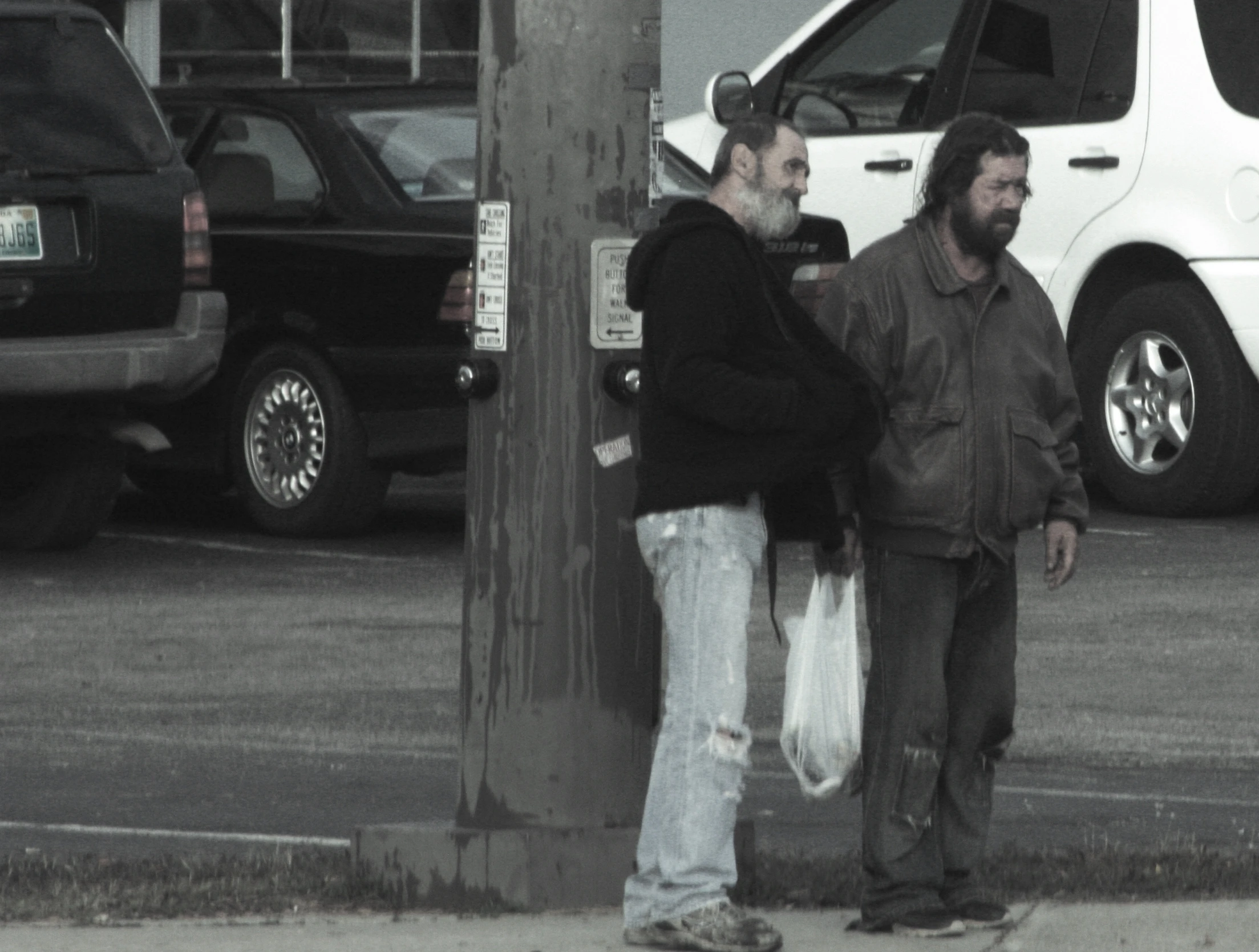 two men standing next to a pole and a van