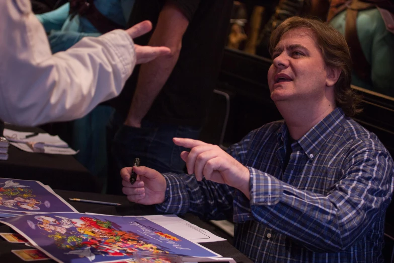 a man sitting at a table talking to other people