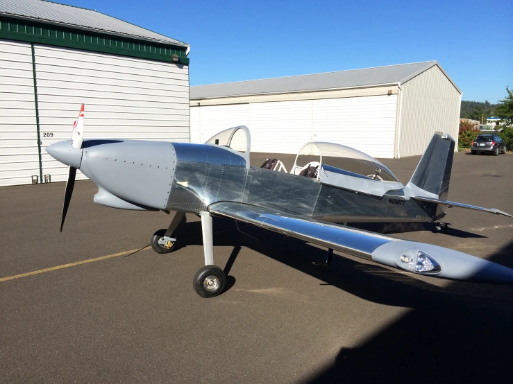 a plane parked in a parking lot next to a hangar