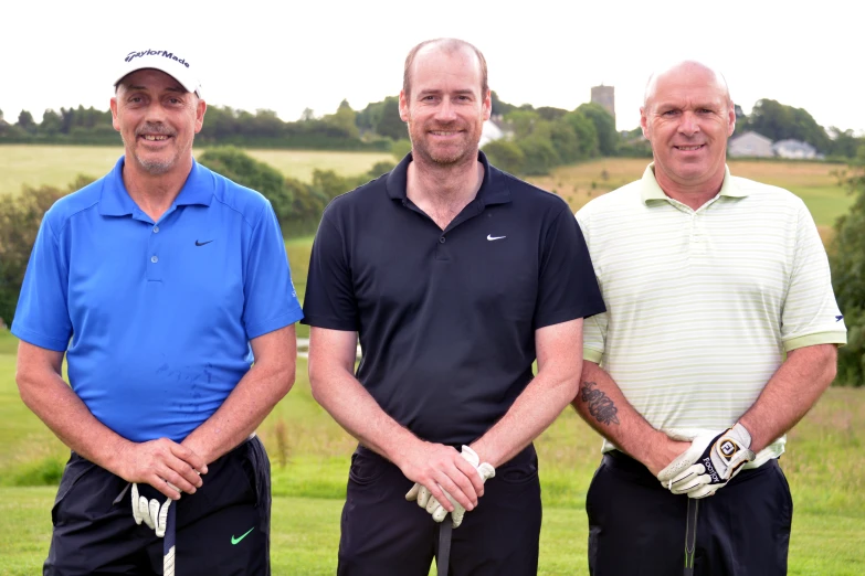 three men stand near each other with golf putters around them