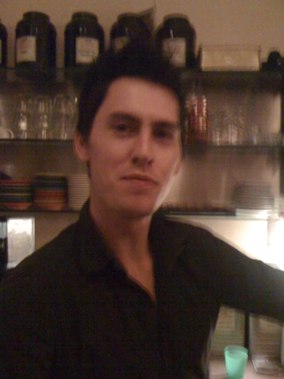 a man is posing in front of shelves and jars